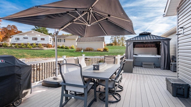 wooden deck featuring a gazebo, a hot tub, grilling area, and a lawn