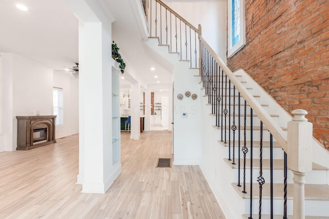 staircase featuring ceiling fan, wood-type flooring, and brick wall