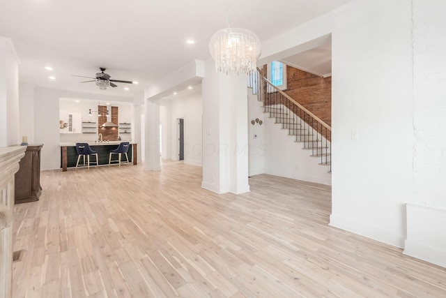 unfurnished living room featuring ceiling fan with notable chandelier, light wood-type flooring, and sink