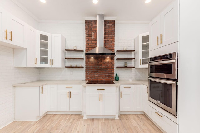 kitchen with white cabinets, light wood-type flooring, and wall chimney range hood