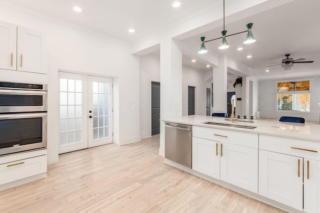 kitchen featuring white cabinetry, sink, ceiling fan, light hardwood / wood-style floors, and appliances with stainless steel finishes