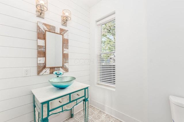 bathroom featuring vanity, toilet, and wood walls