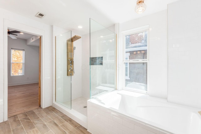 bathroom featuring ceiling fan, shower with separate bathtub, and a wealth of natural light