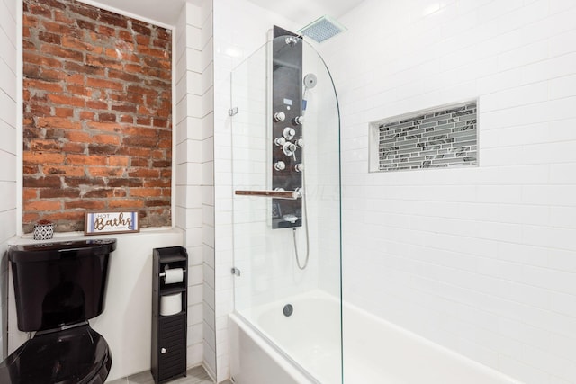 bathroom featuring brick wall and tiled shower / bath