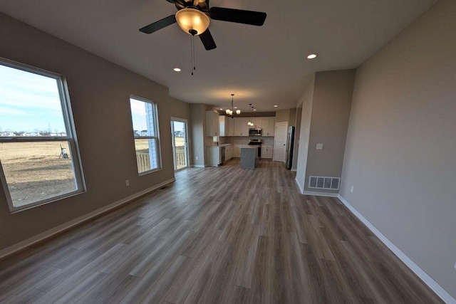 unfurnished living room featuring recessed lighting, visible vents, ceiling fan, wood finished floors, and baseboards