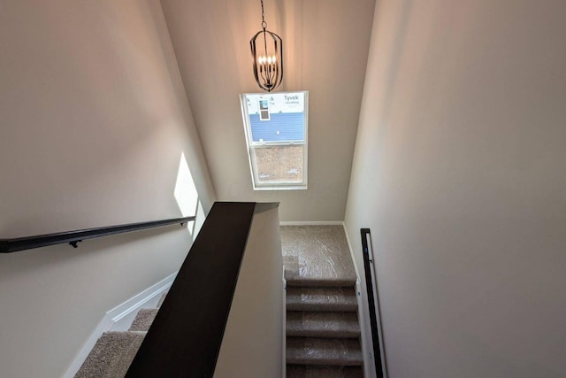 stairs featuring baseboards, a chandelier, and carpet flooring