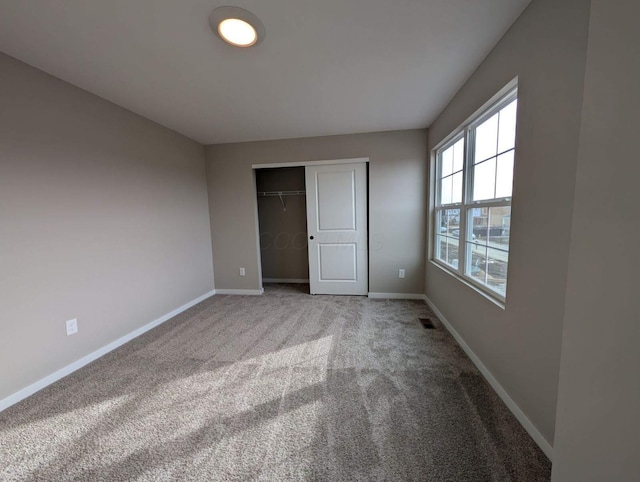 unfurnished bedroom with carpet, baseboards, visible vents, and a closet