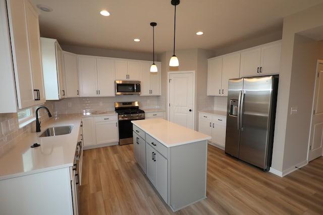 kitchen with a kitchen island, appliances with stainless steel finishes, light countertops, light wood-type flooring, and a sink