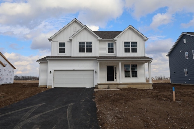 modern inspired farmhouse with aphalt driveway, a shingled roof, covered porch, board and batten siding, and a garage