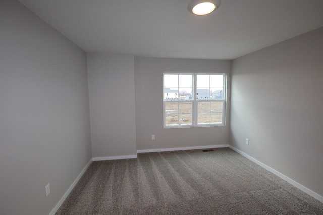 spare room featuring carpet flooring, visible vents, and baseboards