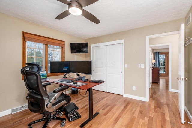 office featuring a wealth of natural light, ceiling fan, and light hardwood / wood-style flooring