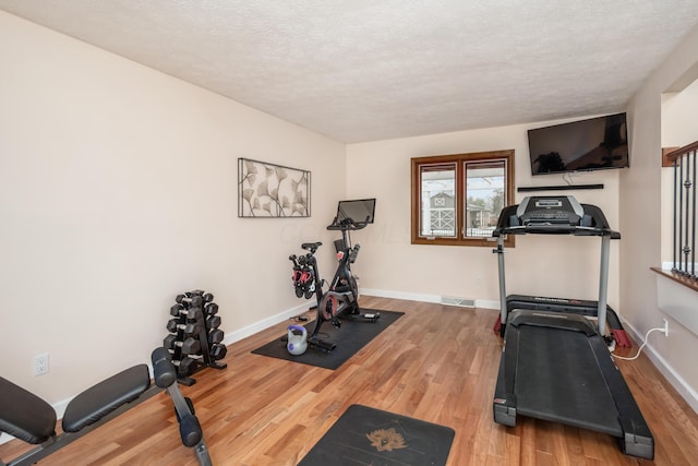 exercise area featuring hardwood / wood-style flooring and a textured ceiling