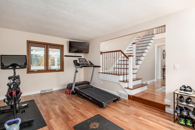 exercise room with wood-type flooring and a textured ceiling