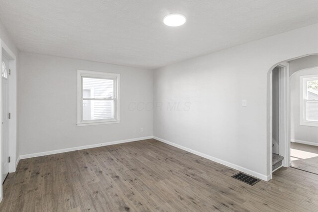 1961 Dartmouth Ave, Columbus, OH 43219 - empty room with arched walkways, plenty of natural light, wood finished floors, and stairs