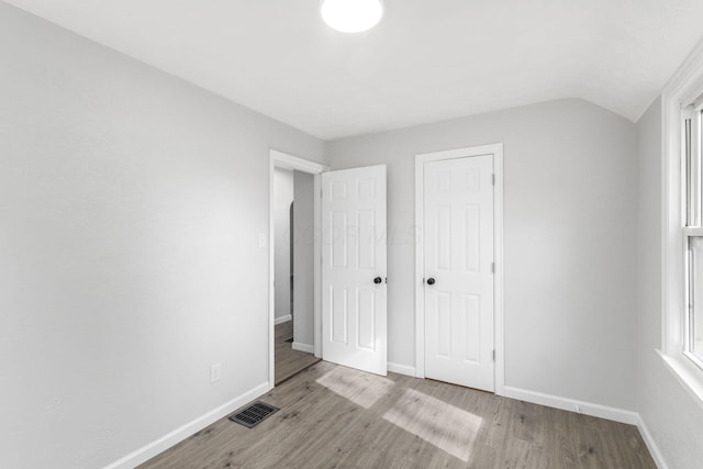 unfurnished bedroom featuring light wood-type flooring and vaulted ceiling