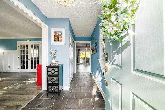 entryway featuring dark hardwood / wood-style floors, crown molding, a textured ceiling, and french doors