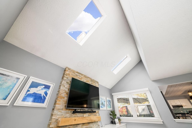 living room featuring high vaulted ceiling and a skylight