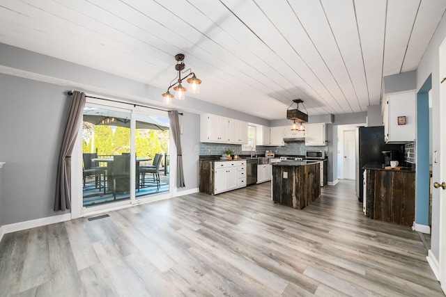 kitchen with tasteful backsplash, light hardwood / wood-style flooring, a center island, white cabinetry, and hanging light fixtures