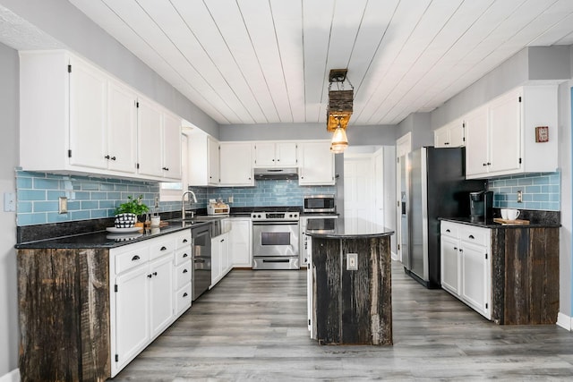 kitchen with white cabinets, a kitchen island, stainless steel appliances, and wood-type flooring