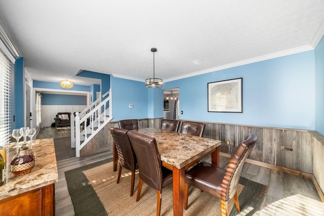 dining room with dark hardwood / wood-style floors, ornamental molding, a textured ceiling, and wooden walls