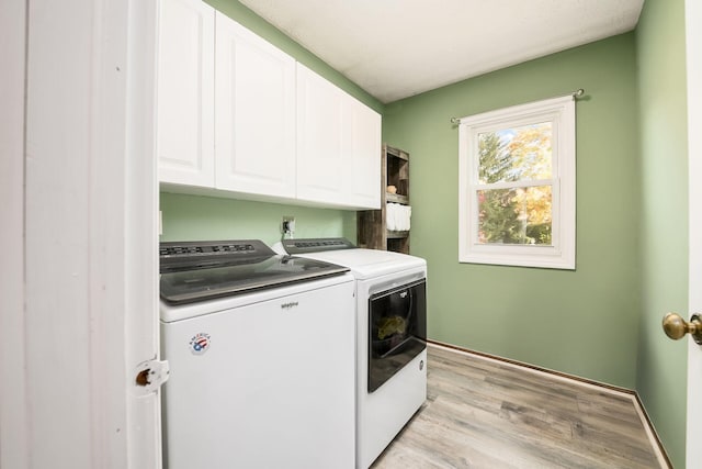 laundry room featuring cabinets, washing machine and dryer, and light wood-type flooring