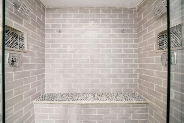 bathroom with a tile shower and a textured ceiling