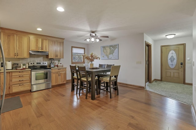 kitchen featuring light brown cabinets, light wood-type flooring, ceiling fan, and stainless steel range with electric cooktop