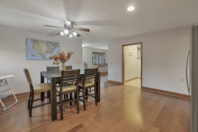 dining space with ceiling fan, wood-type flooring, and a textured ceiling