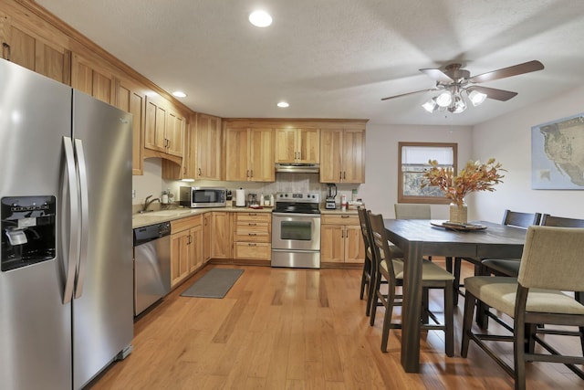 kitchen with ceiling fan, light hardwood / wood-style floors, decorative backsplash, light brown cabinetry, and appliances with stainless steel finishes