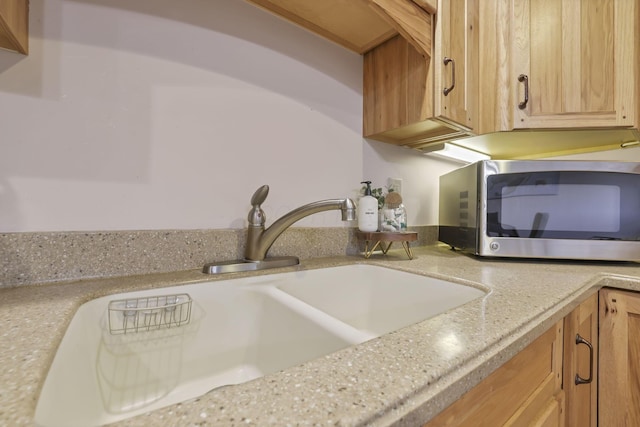 kitchen with light brown cabinets, light stone countertops, and sink