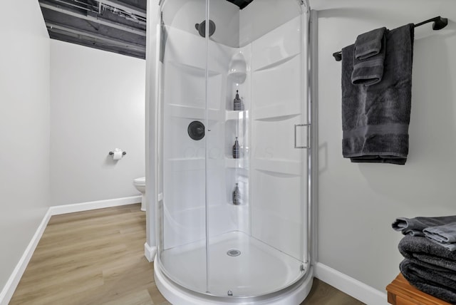 bathroom featuring wood-type flooring, toilet, and a shower with door