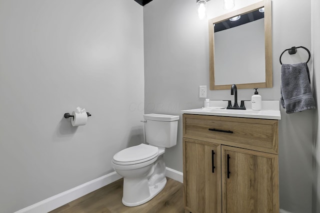 bathroom with toilet, vanity, and hardwood / wood-style flooring