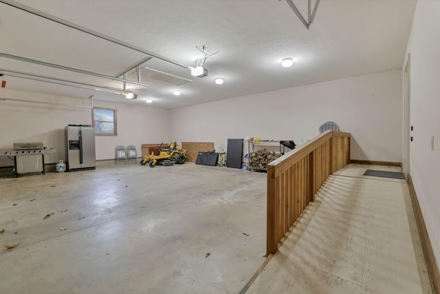 garage with stainless steel fridge and a garage door opener