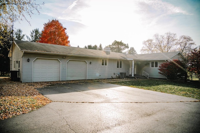 single story home with central AC, a front lawn, and a garage