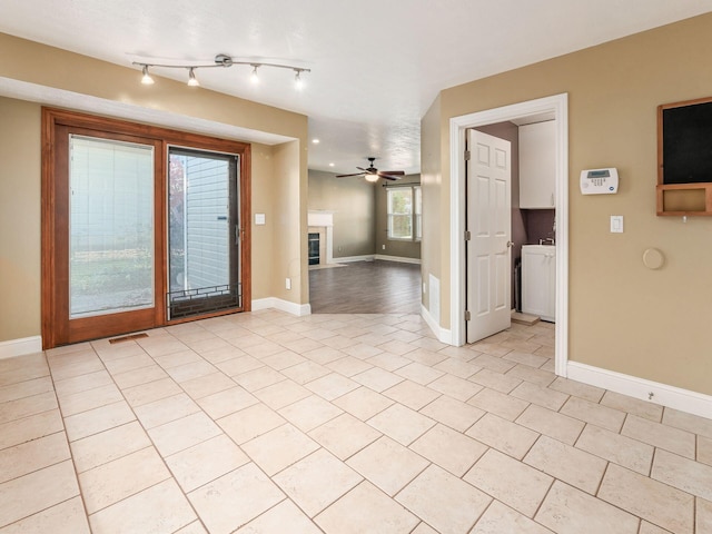 tiled empty room with ceiling fan and washer / dryer