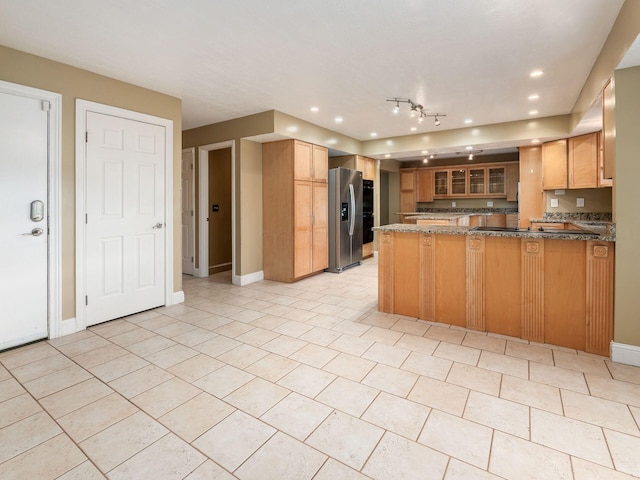 kitchen featuring dark stone countertops, light tile patterned flooring, kitchen peninsula, and stainless steel refrigerator with ice dispenser