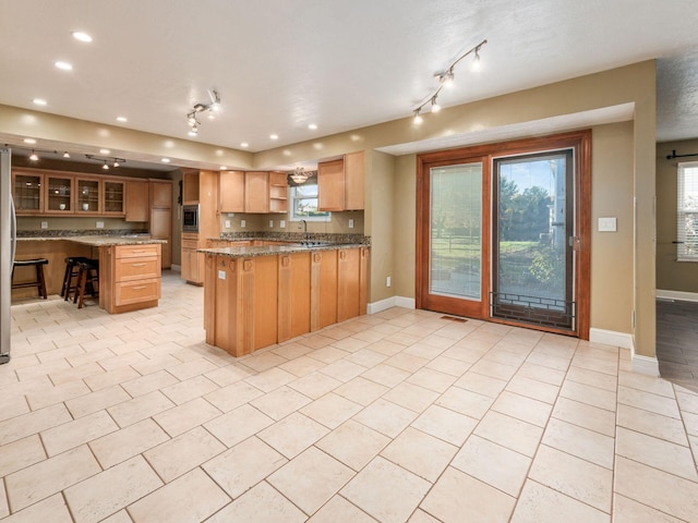 kitchen featuring light tile patterned floors, sink, stone counters, stainless steel appliances, and kitchen peninsula