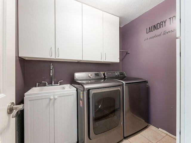 laundry area featuring light tile patterned flooring, washer and dryer, sink, cabinets, and a textured ceiling