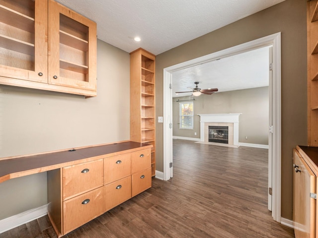 kitchen featuring ceiling fan, dark wood-type flooring, built in desk, and a textured ceiling