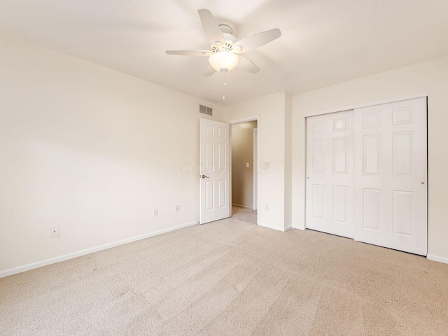 unfurnished bedroom featuring light carpet, ceiling fan, and a closet