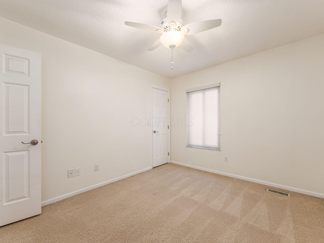 carpeted empty room with ceiling fan and a textured ceiling