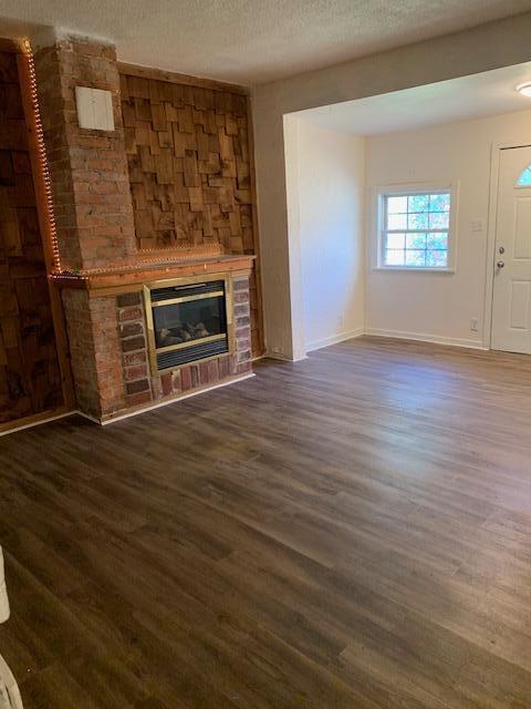 unfurnished living room with a textured ceiling and dark hardwood / wood-style floors