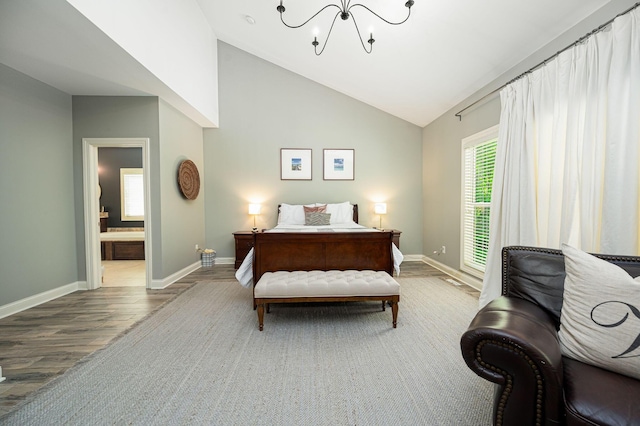 bedroom with ensuite bath, multiple windows, wood-type flooring, and lofted ceiling