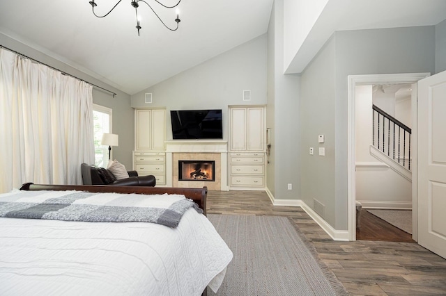 bedroom with a fireplace, high vaulted ceiling, a chandelier, and hardwood / wood-style flooring