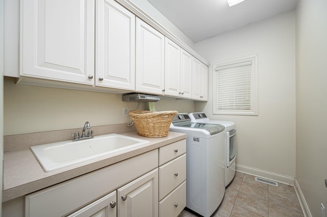 laundry room featuring cabinets, light tile patterned floors, washing machine and dryer, and sink