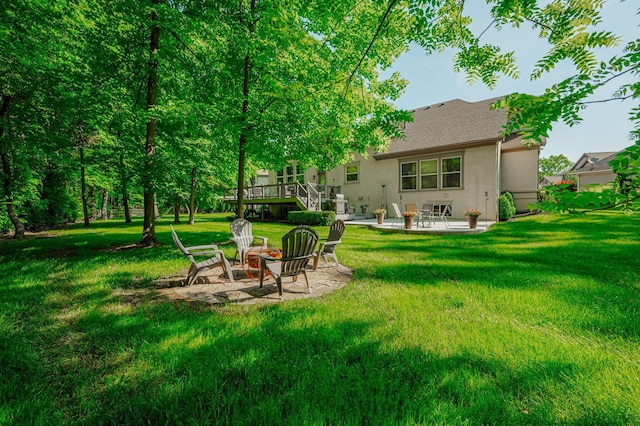 back of property with a deck, an outdoor fire pit, a patio area, and a lawn