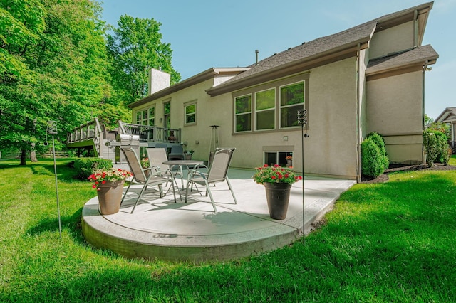 back of property with a wooden deck, a patio area, and a lawn