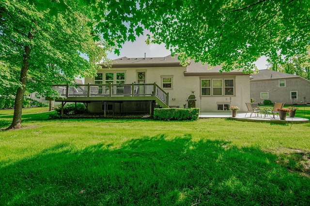 rear view of property with a deck, a patio area, and a lawn