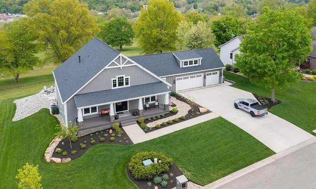 view of front of house featuring covered porch, a front lawn, a garage, and cooling unit