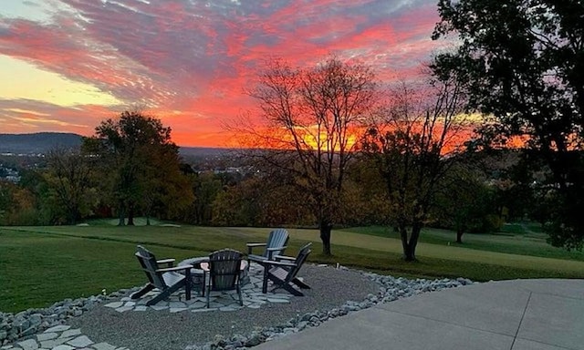 patio terrace at dusk with a lawn and a fire pit